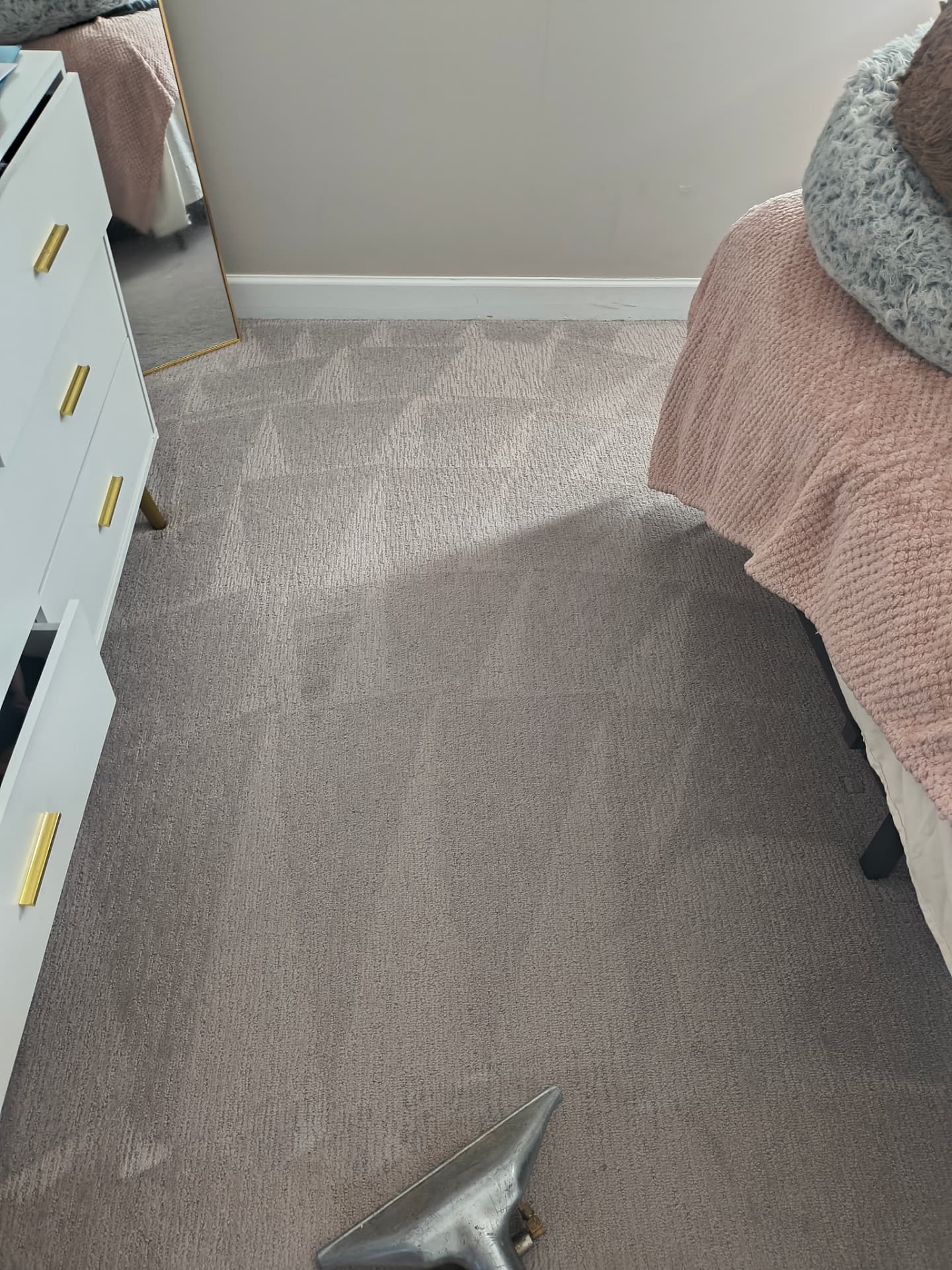 A close-up of carpet cleaning beside a bed