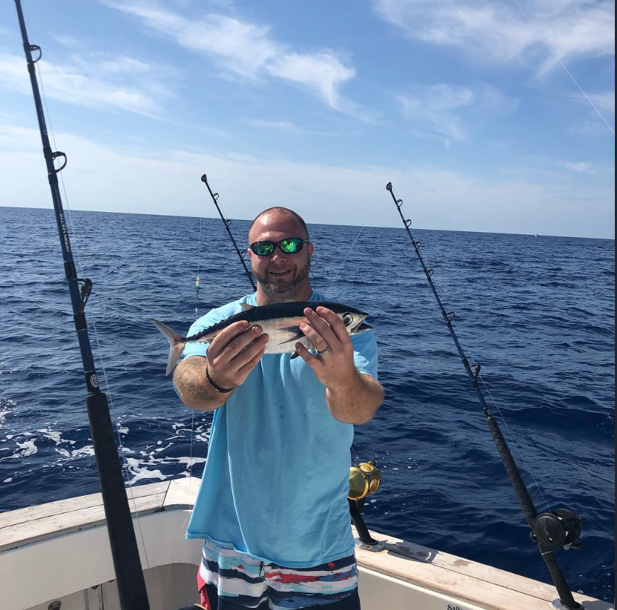 Jeremy Goding holding a fish on a boat, remembered fondly